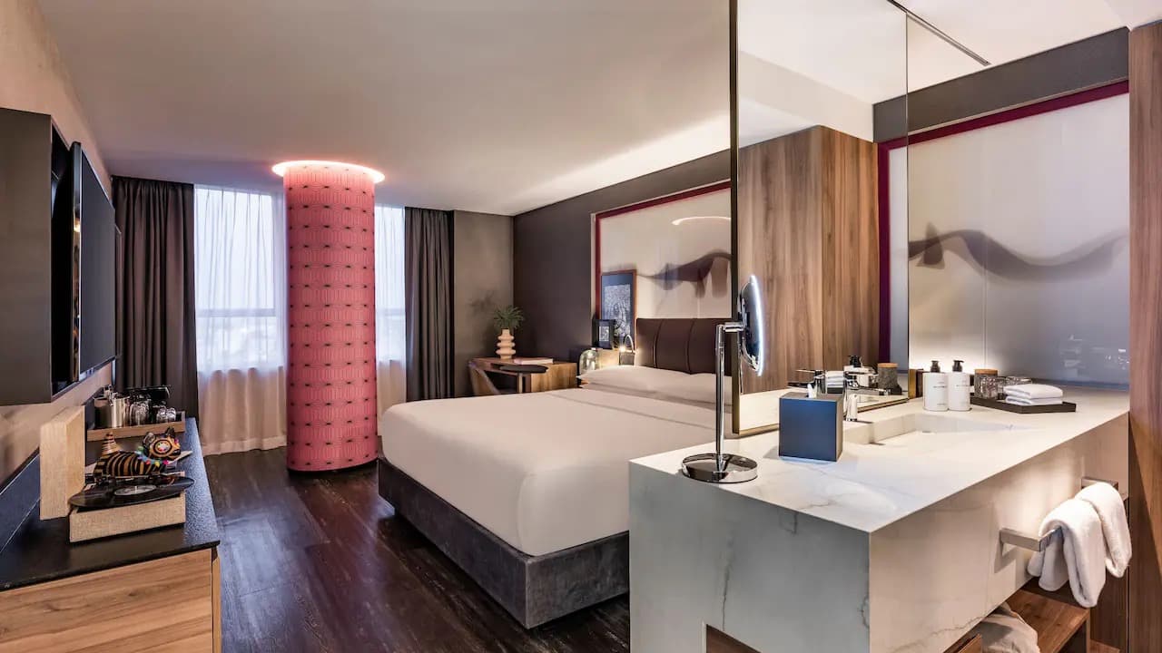 A standard king room at the Andaz with dark wood floors and a marble vanity